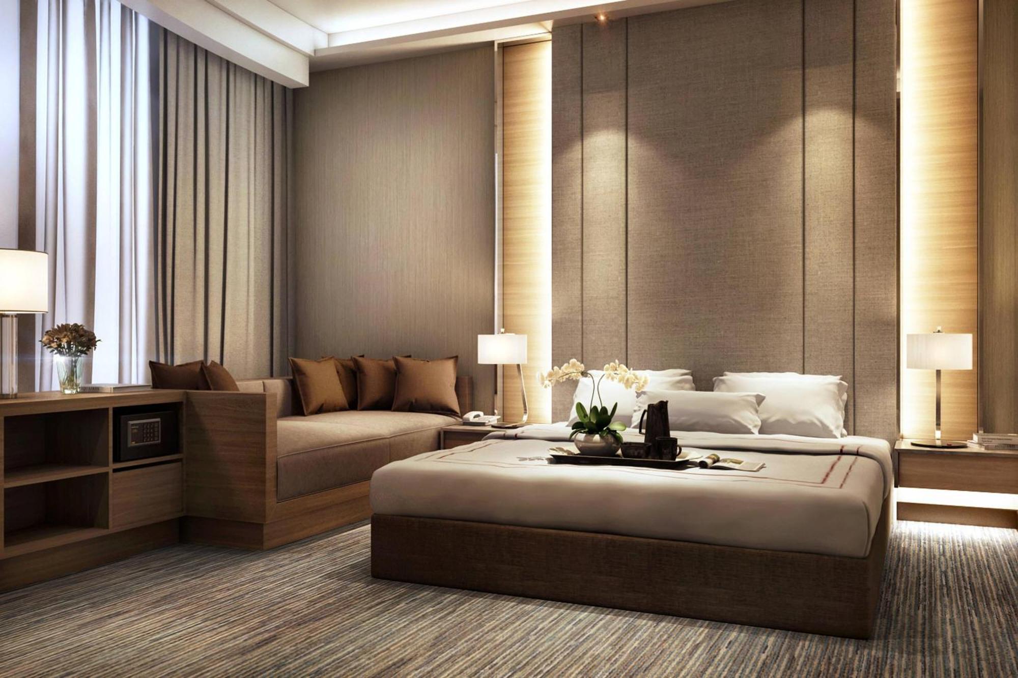 فندق جيه.دابليو ماريوت، كوالالمبور المظهر الخارجي الصورة The photo depicts a modern and stylish bedroom. It features a large bed with neutral-colored bedding and an elegant headboard. On either side of the bed, there are bedside tables with contemporary lamps. There's a cozy seating area with a sofa adorne